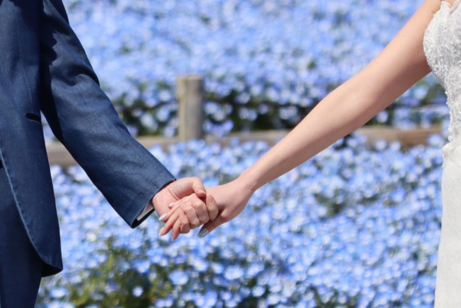 紫の花を背景に、結婚し手を繋ぐ男女