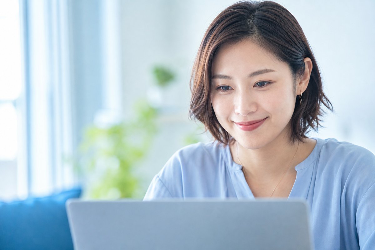 30代の女性がノートパソコンの前で表情を和らげ、安心した様子で小さく微笑んでいる