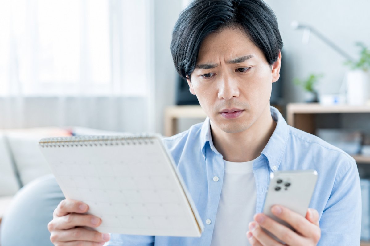 30代の男性がカレンダーとスマートフォンの画面を見比べながら、いつから手当を受け取れるのか心配そうな顔をしている