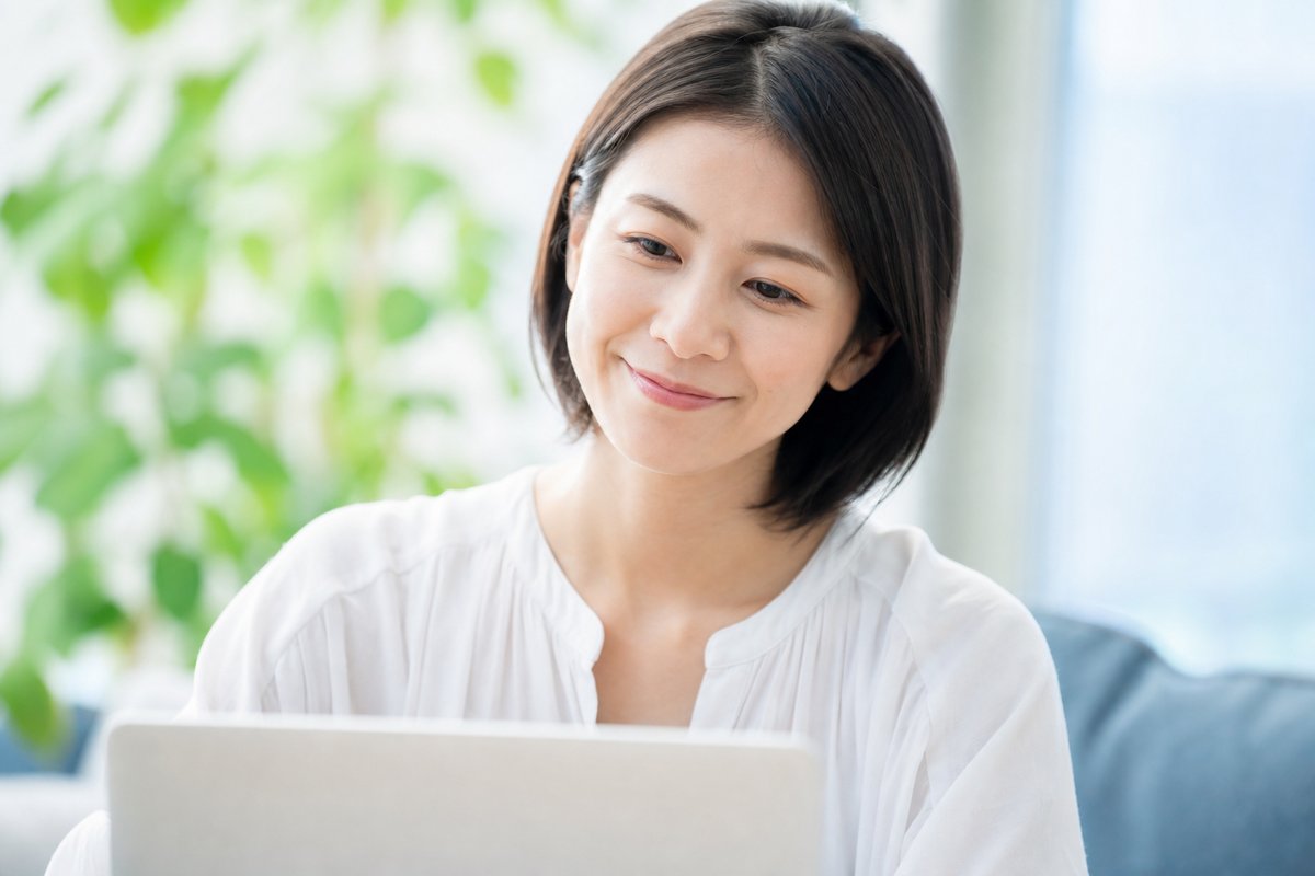 30代の女性がノートパソコンの前で穏やかな笑顔を浮かべ、安心した様子でうなずいている