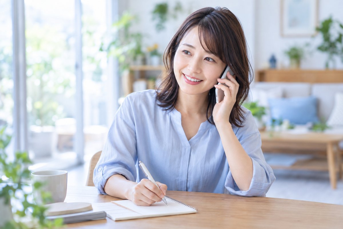30代の女性がスマートフォンを耳に当てて相談窓口と話しながら、手元のメモに書き留めている